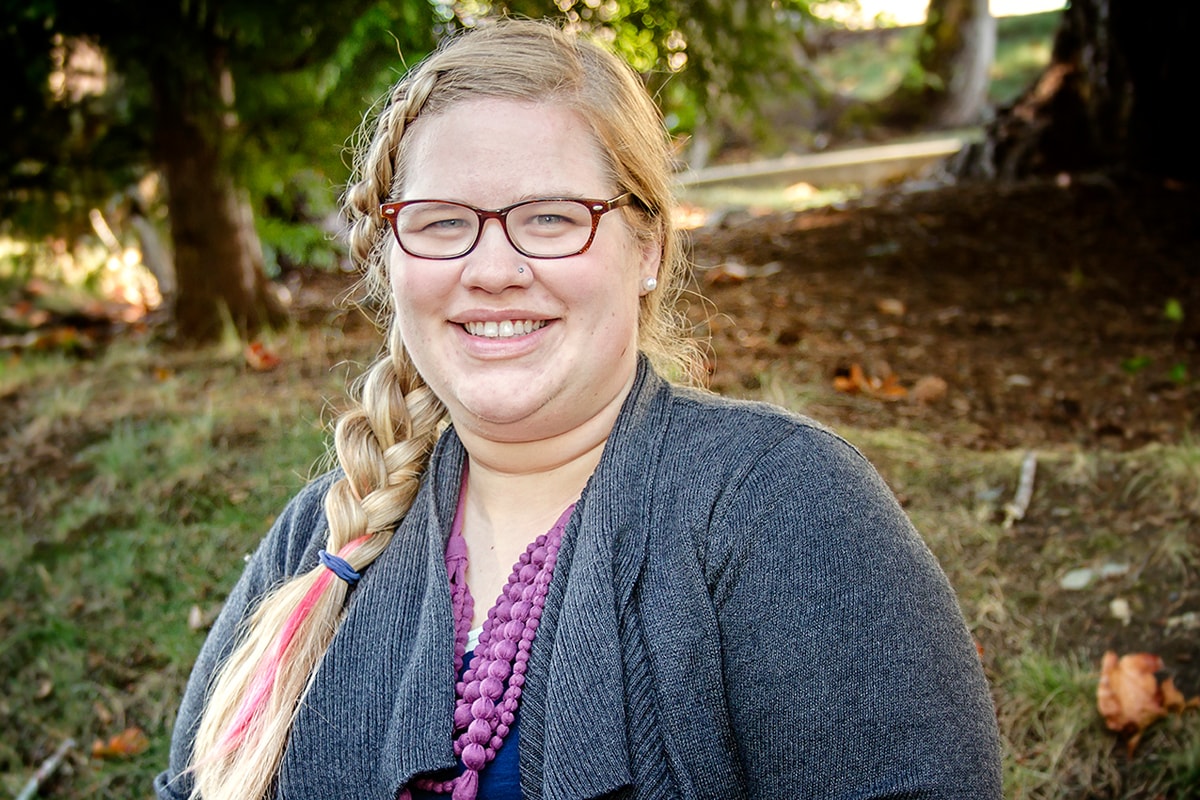 DigiPen Student Life Advisor Alyssa Voyles smiling in a wooded area on the DigiPen campus