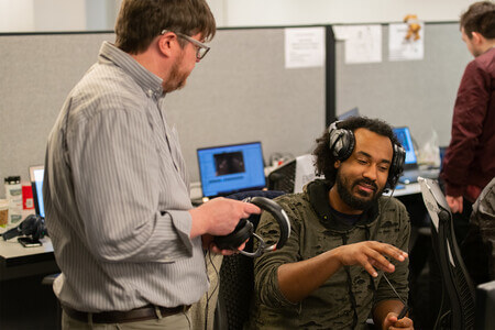 A DigiPen student talks with an instructor in the production lab.