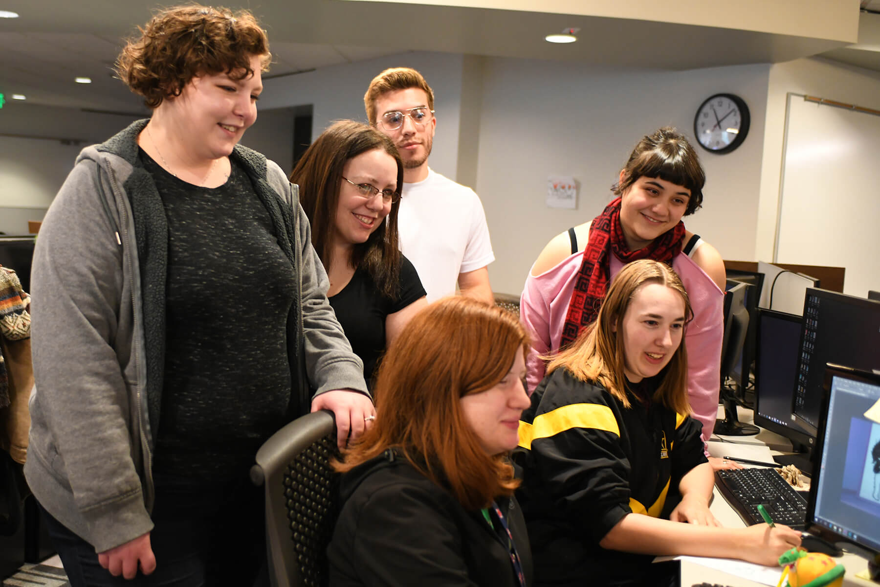 A DigiPen game team smiles as they look at art their team member made on a computer.