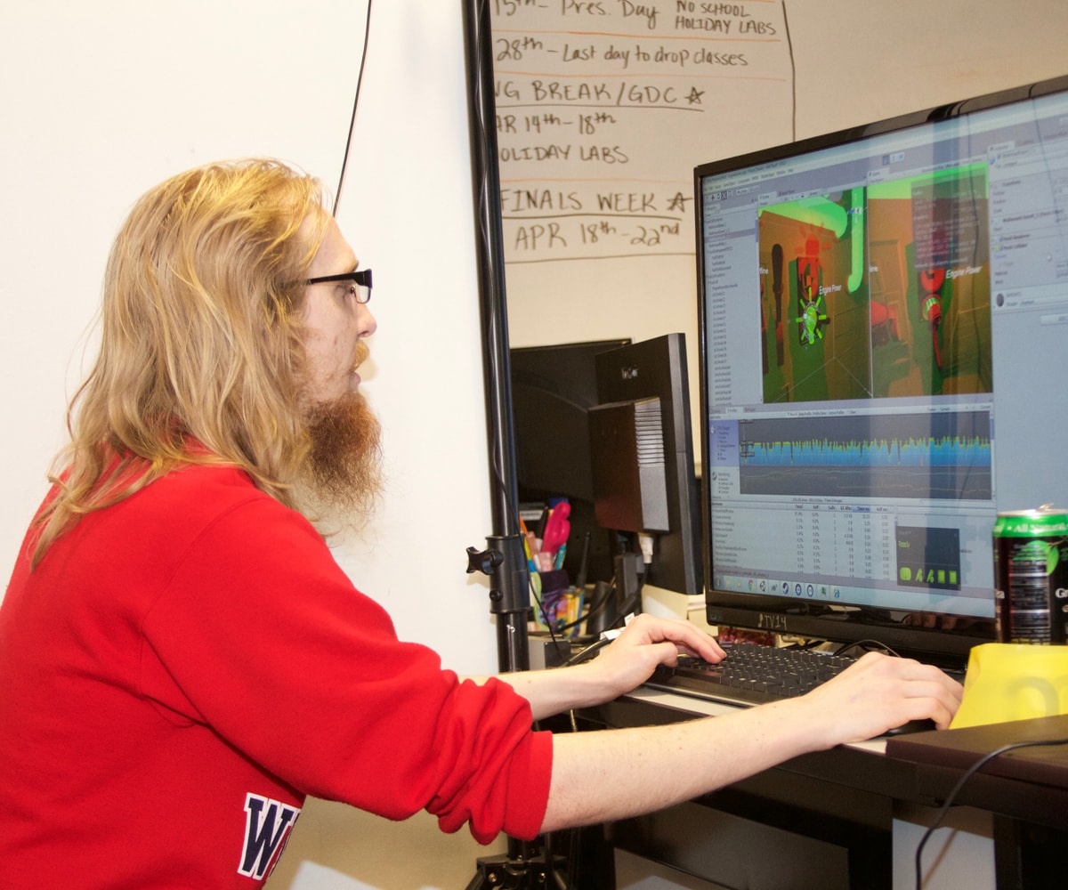 DigiPen student Bryan Willey sits in front of a large monitor with his hands on a keyboard