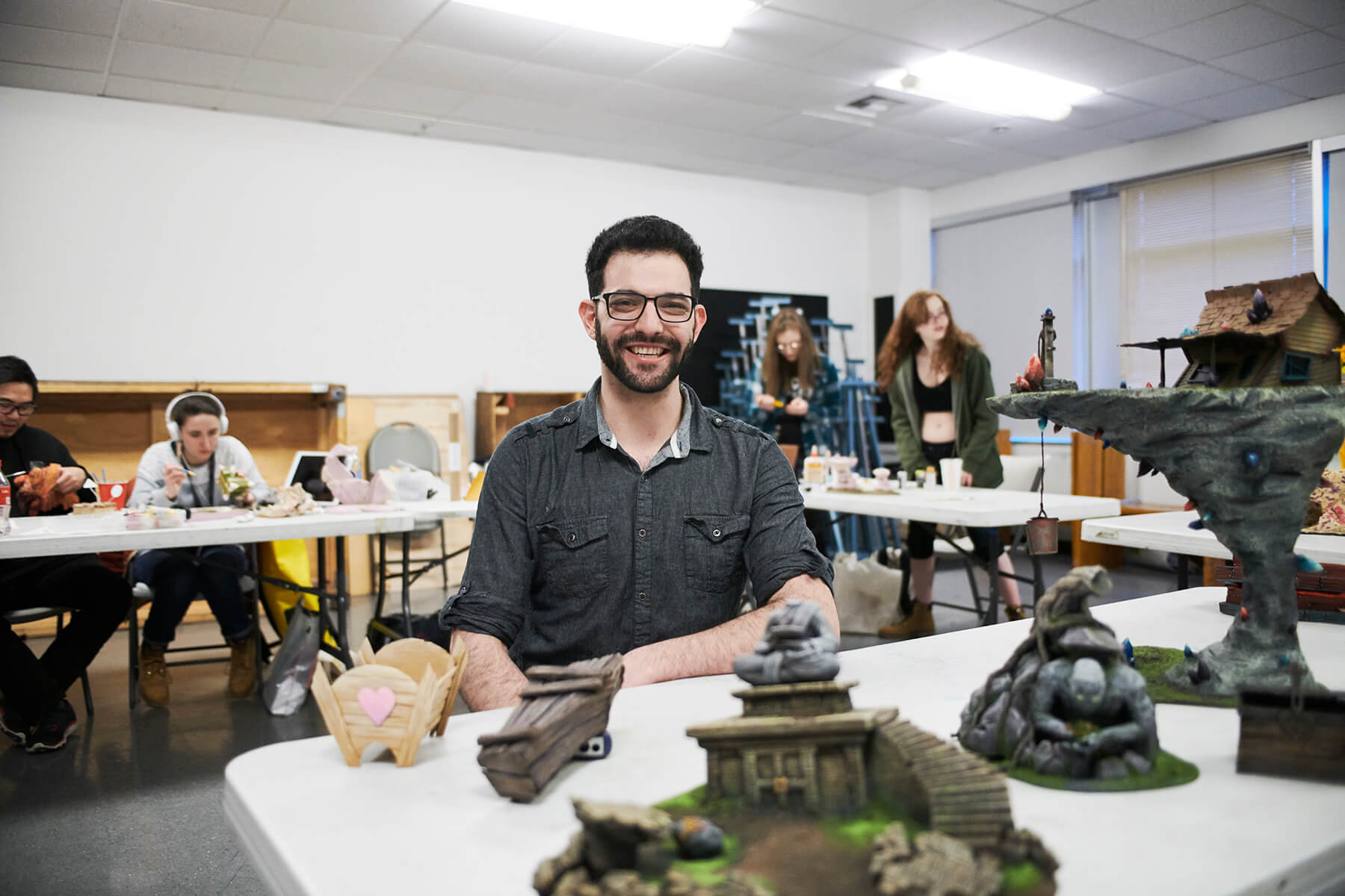 Danny Samuels smiling in front of a table filled with miniatures