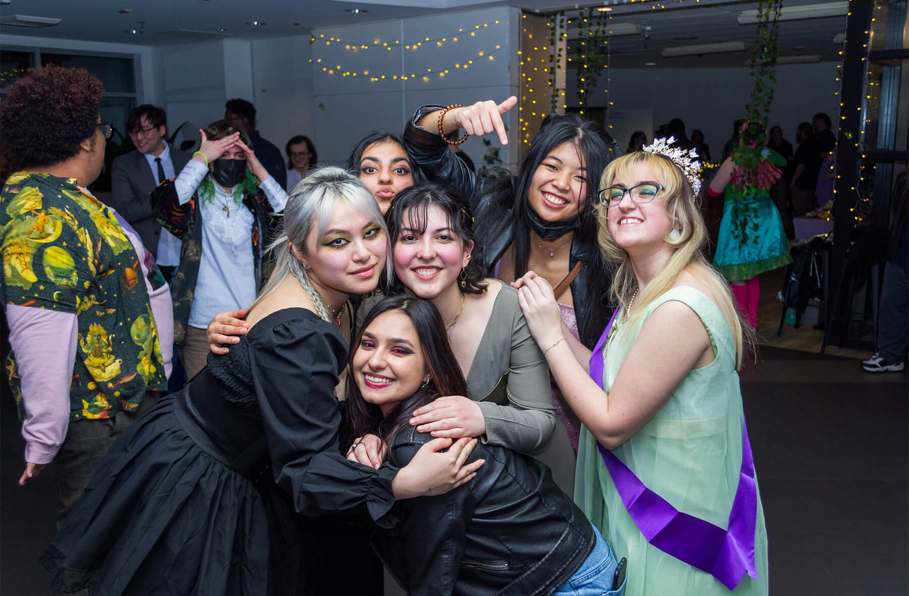 Six DigiPen students huddle together and pose for the camera on the dancefloor at DigiProm.