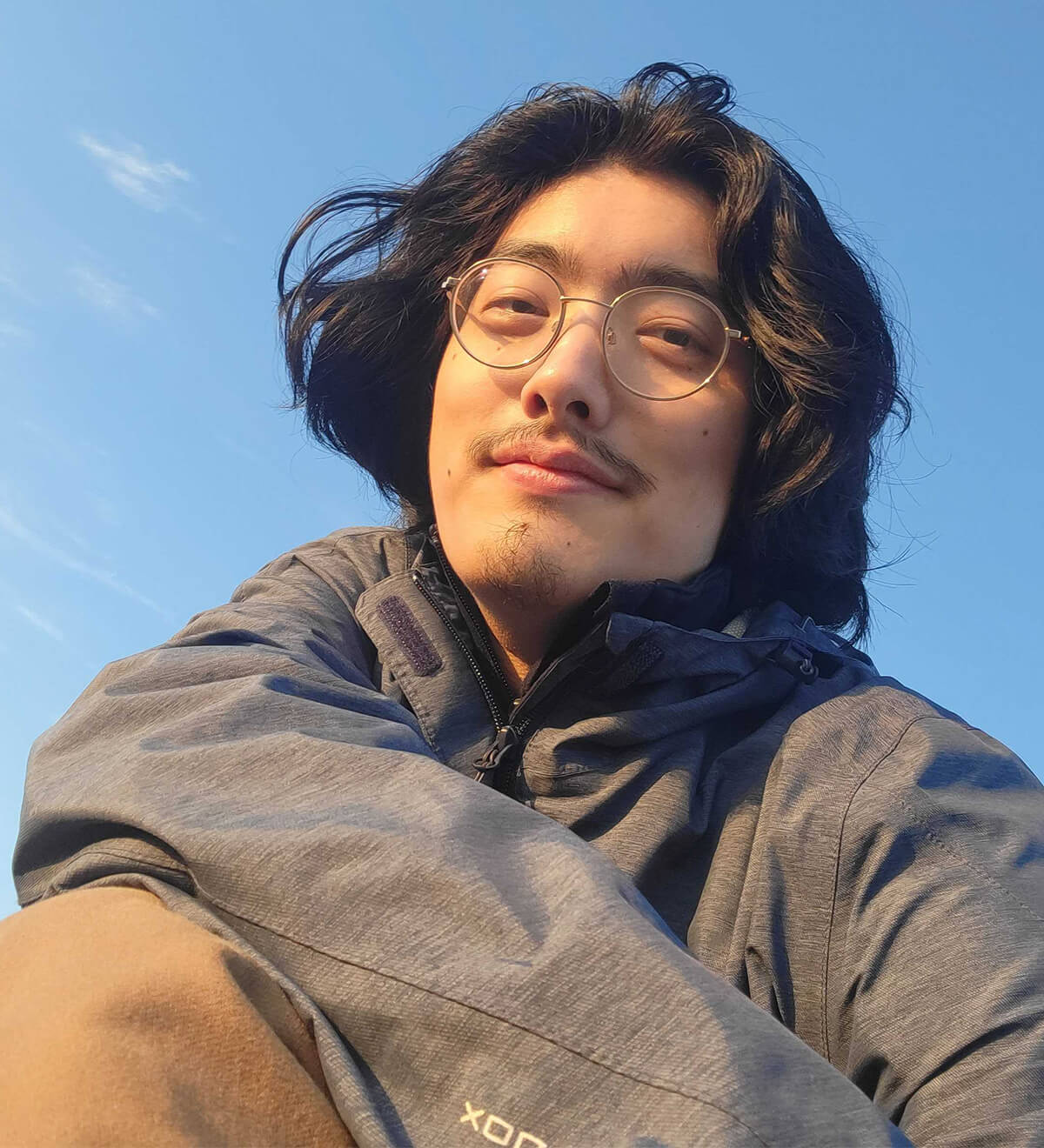 A low angle shot of DigiPen graduate Brandon Yuan against a blue sky.