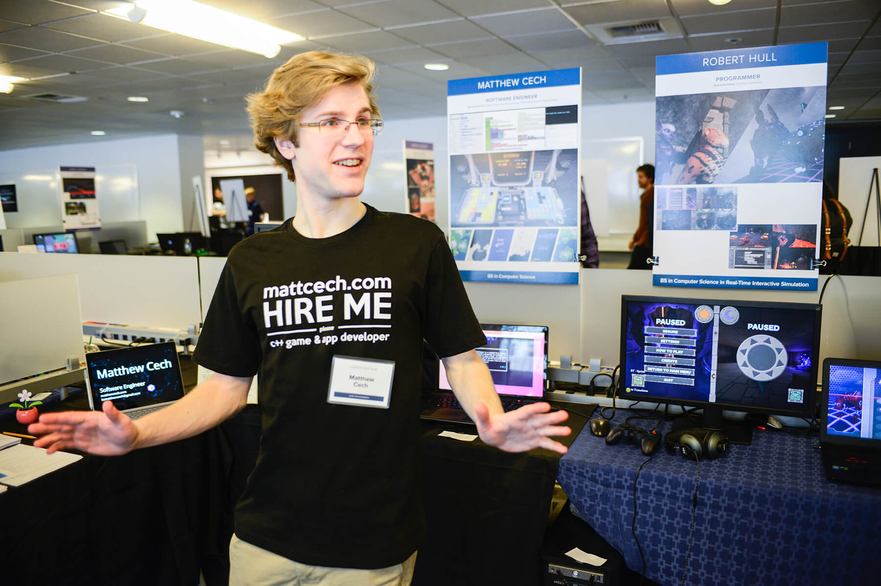 DigiPen student Matt Cech wearing a t-shirt that says "Hire Me" and gives his website address