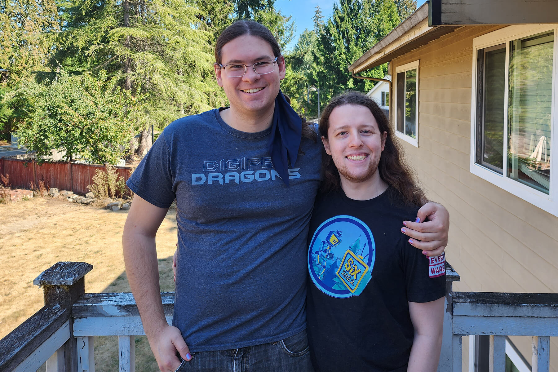 Micah Rust and Tucker Bane pose arm and arm on a forested back porch.