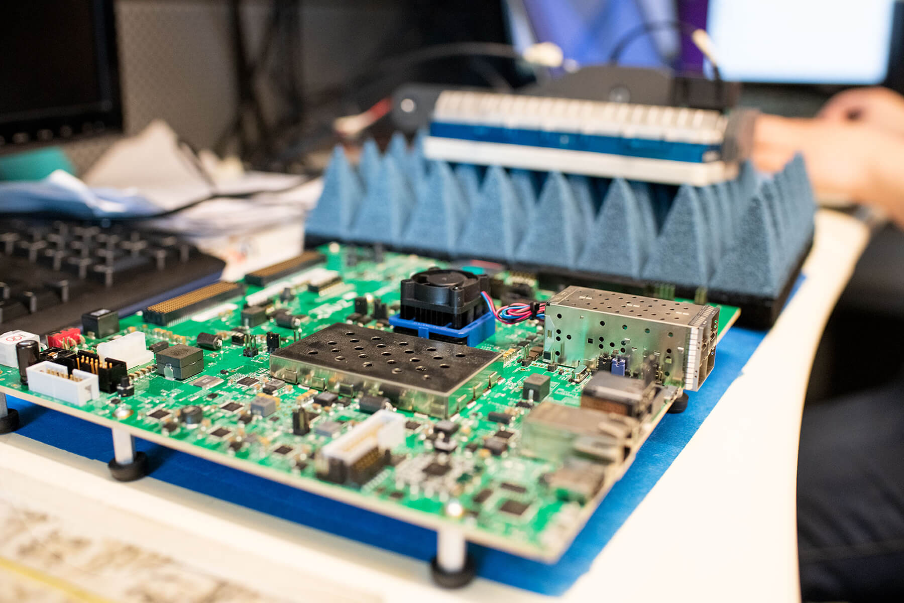 Close-up of an exposed circuit board on a desk connected to a compact radar system resting on foam in the background.