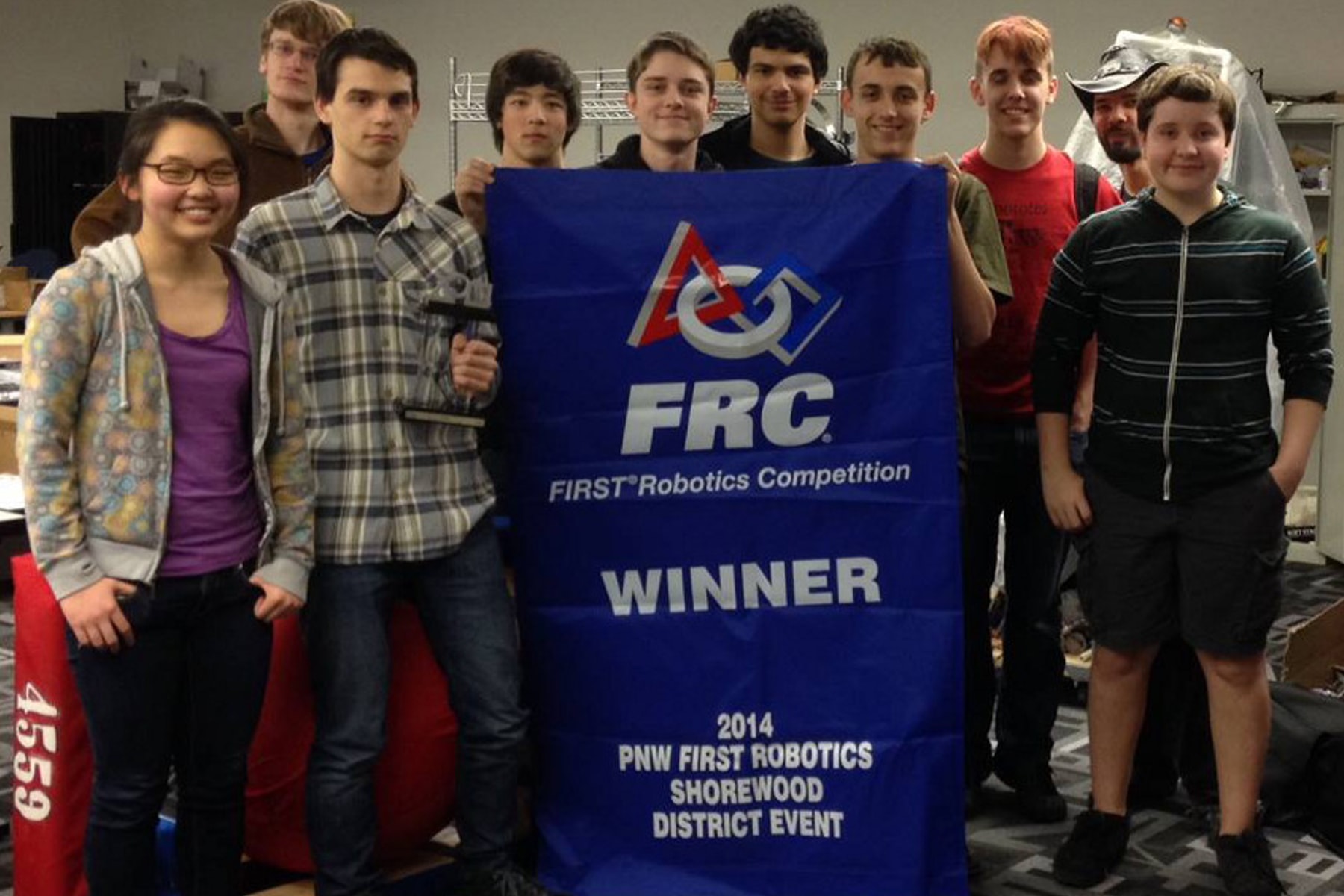 Nine students and one coach of first draft standing around Shorewood District Championship banner