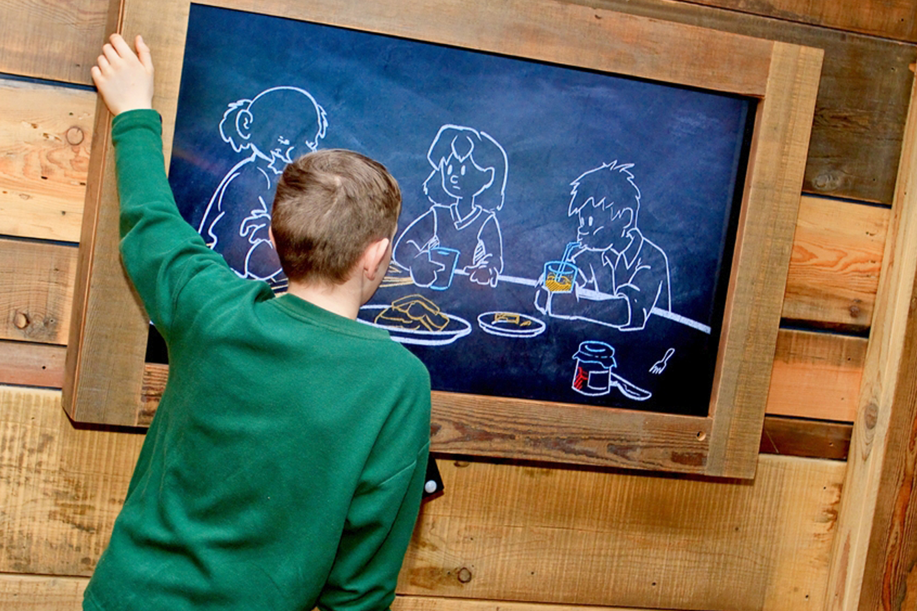 A child watching Hygiene 101 on a monitor built into a wooden wall