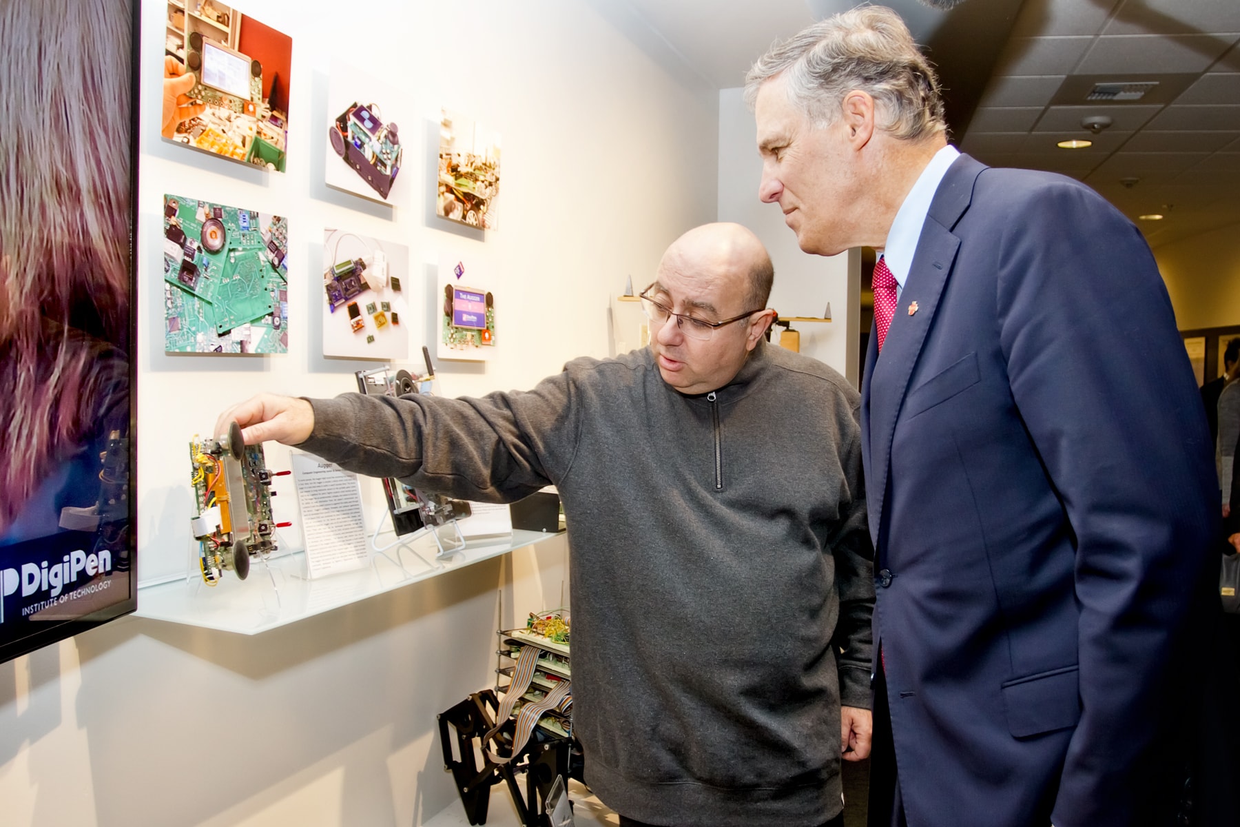Claude Comair showing Governor Jay Inslee an example of computer engineering student work displayed in the DigiPen building