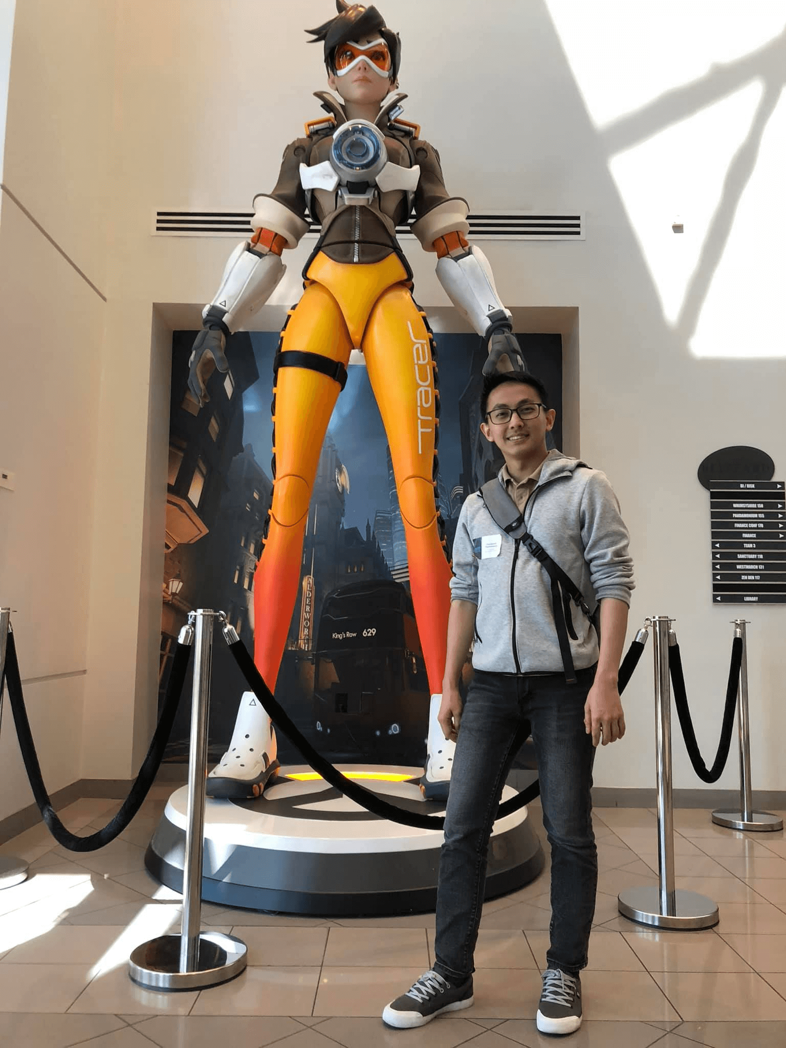 Chonlawat Thammawan stands in front of a towering statue of Tracer from the game Overwatch.