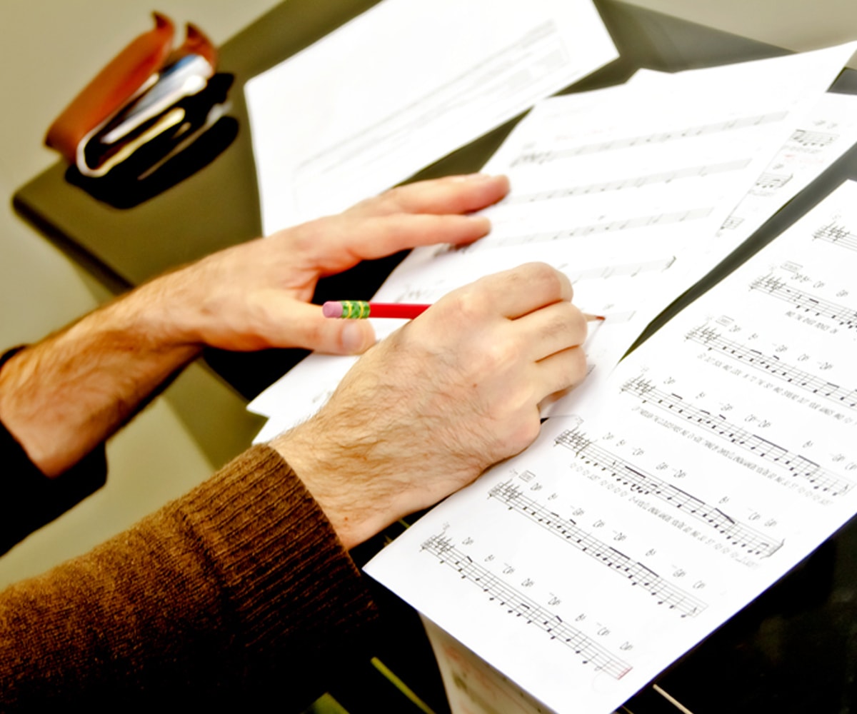 DigiPen student marking sheet music with a red pencil