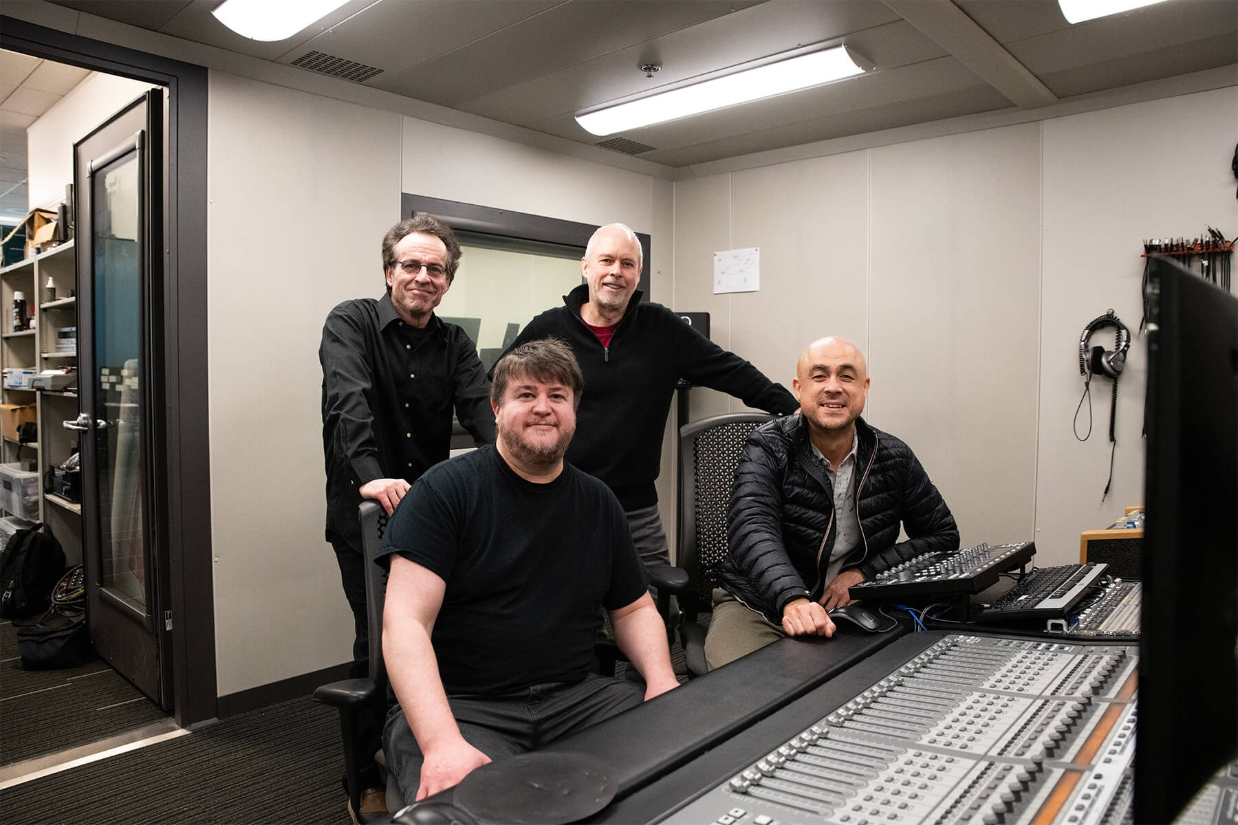 Bruce Stark and Lawrence Schwedler stand behind Greg Dixon and Tacket Brown, seated at a large mixing board.