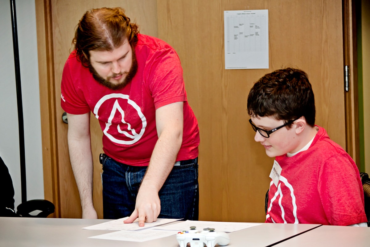 DigiPen student Devin Jensen pointing to a piece of paper, talking with Mason