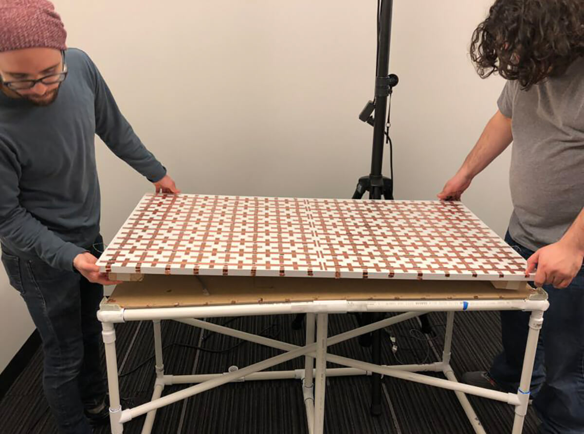 Sound designer Dustin Williams and interaction designer Jason Eldred lower Guerrilla Nouveau's DIY tabletop touchscreen, made from a grid of copper tape, onto the frame