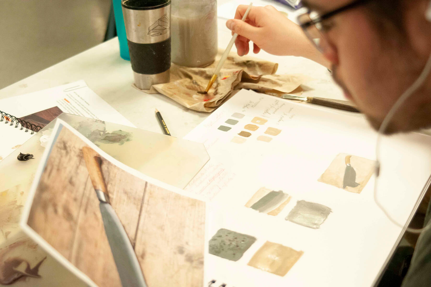 A DigiPen student works on a painting on a desk.