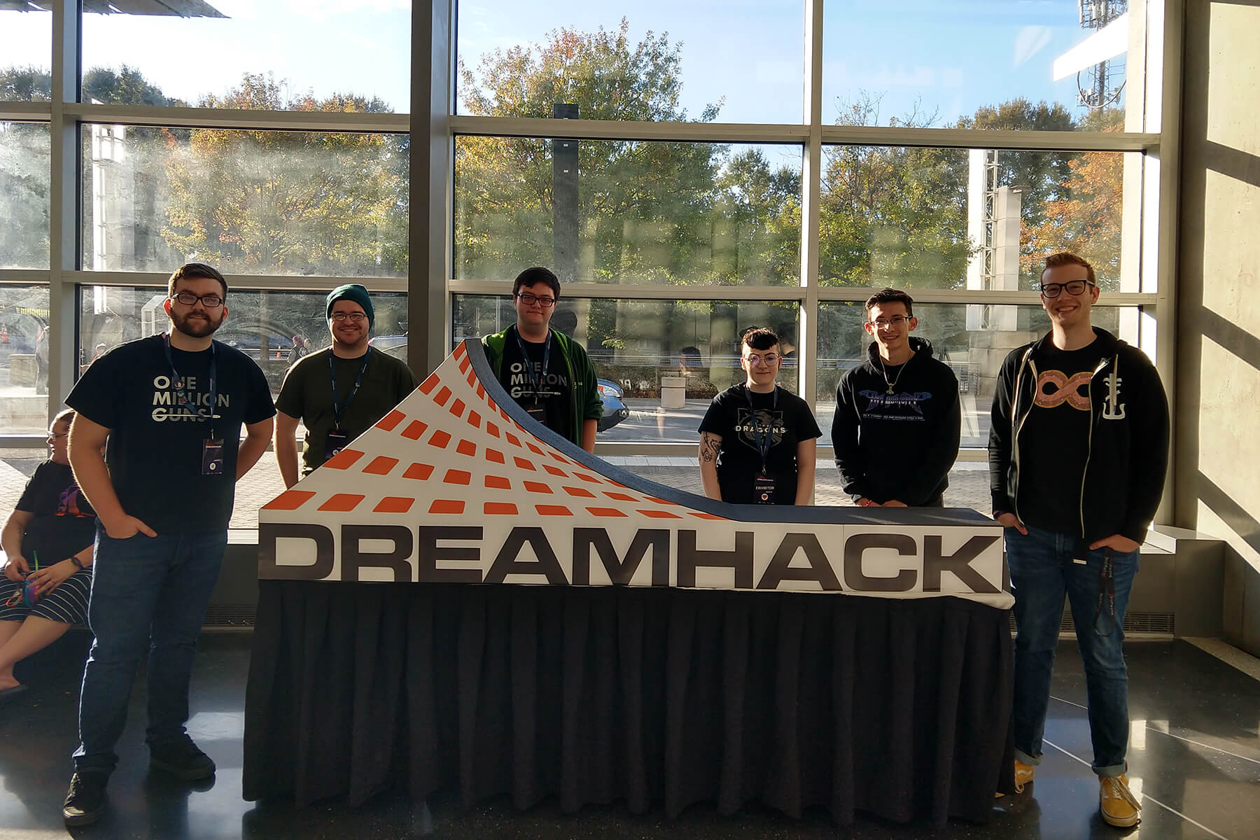 Six DigiPen students stand around a table with the DreamHack logo.