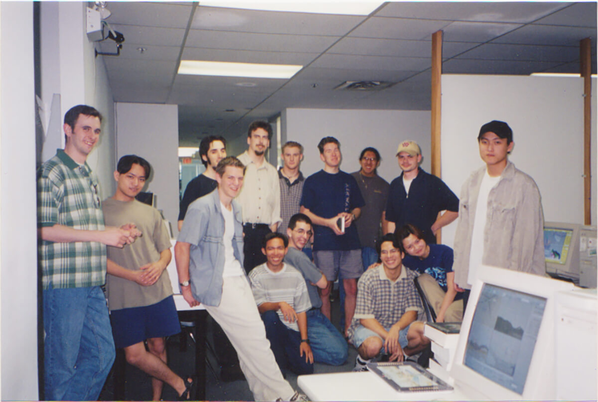 Duncan Shields poses with 13 fellow students in a computer lab at DigiPen Vancouver.