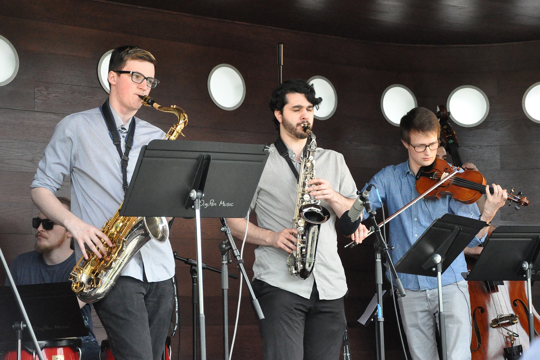 DigiPen Jazz Ensemble members playing saxophones, drums and violin on a portable stage 