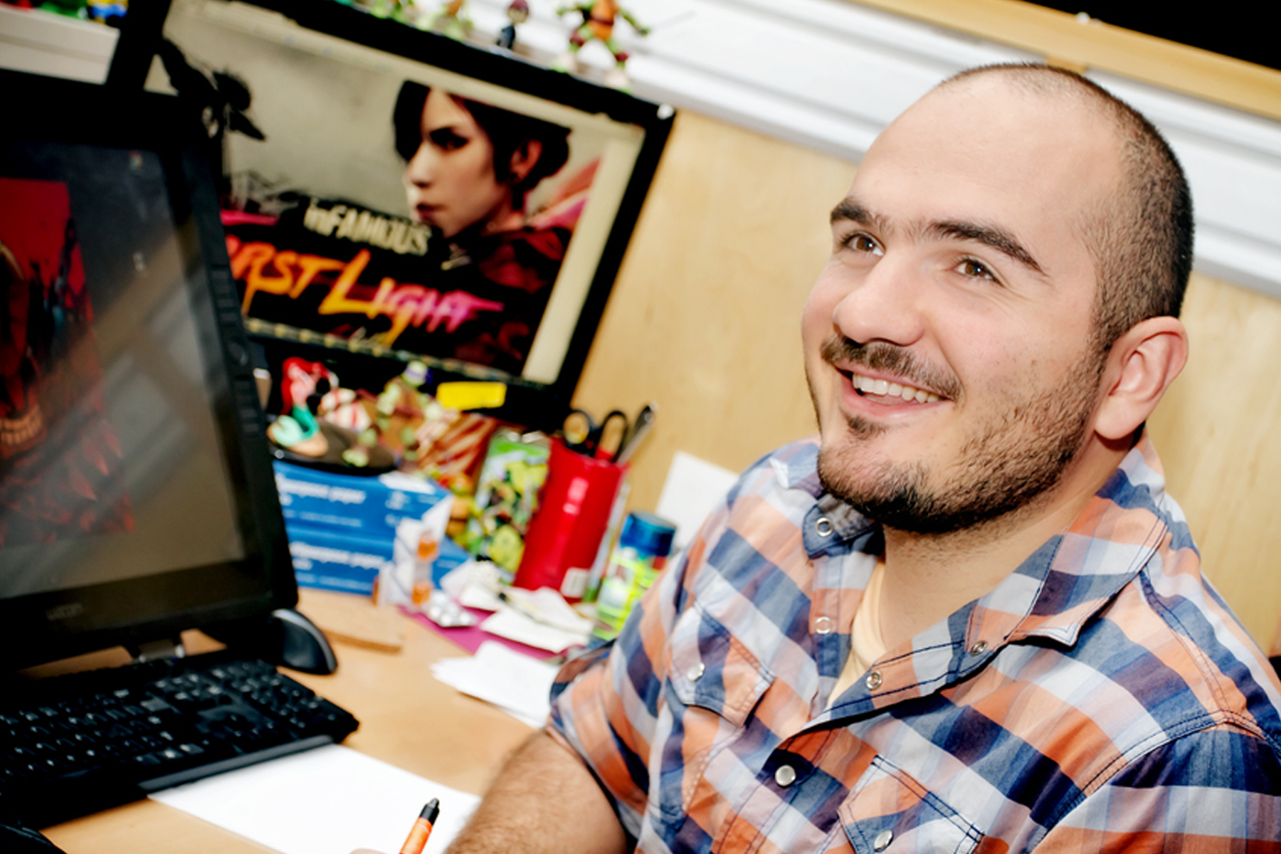 DigiPen alumnus Horia Dociu smiling at his desk in the Sucker Punch Productions office