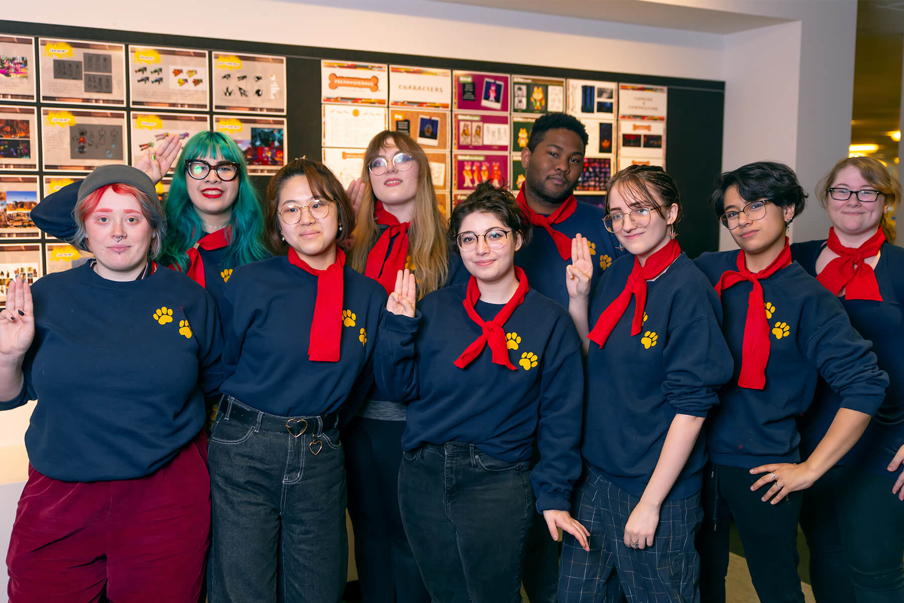 DigiPen film team Happy Campers pose in front of a wall full of animation style guides.