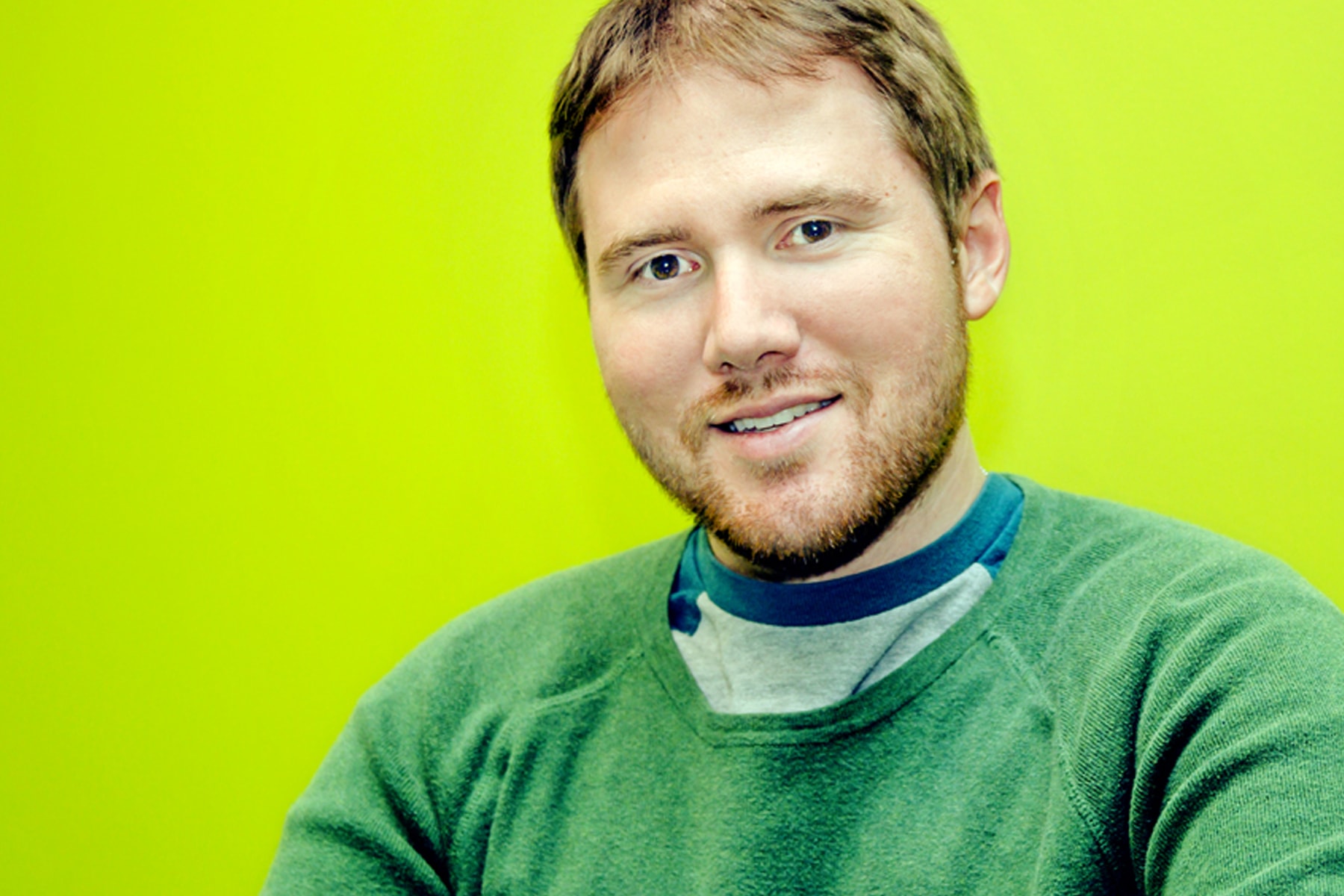 Jon Sourbeer smiling in front of an acid green wall