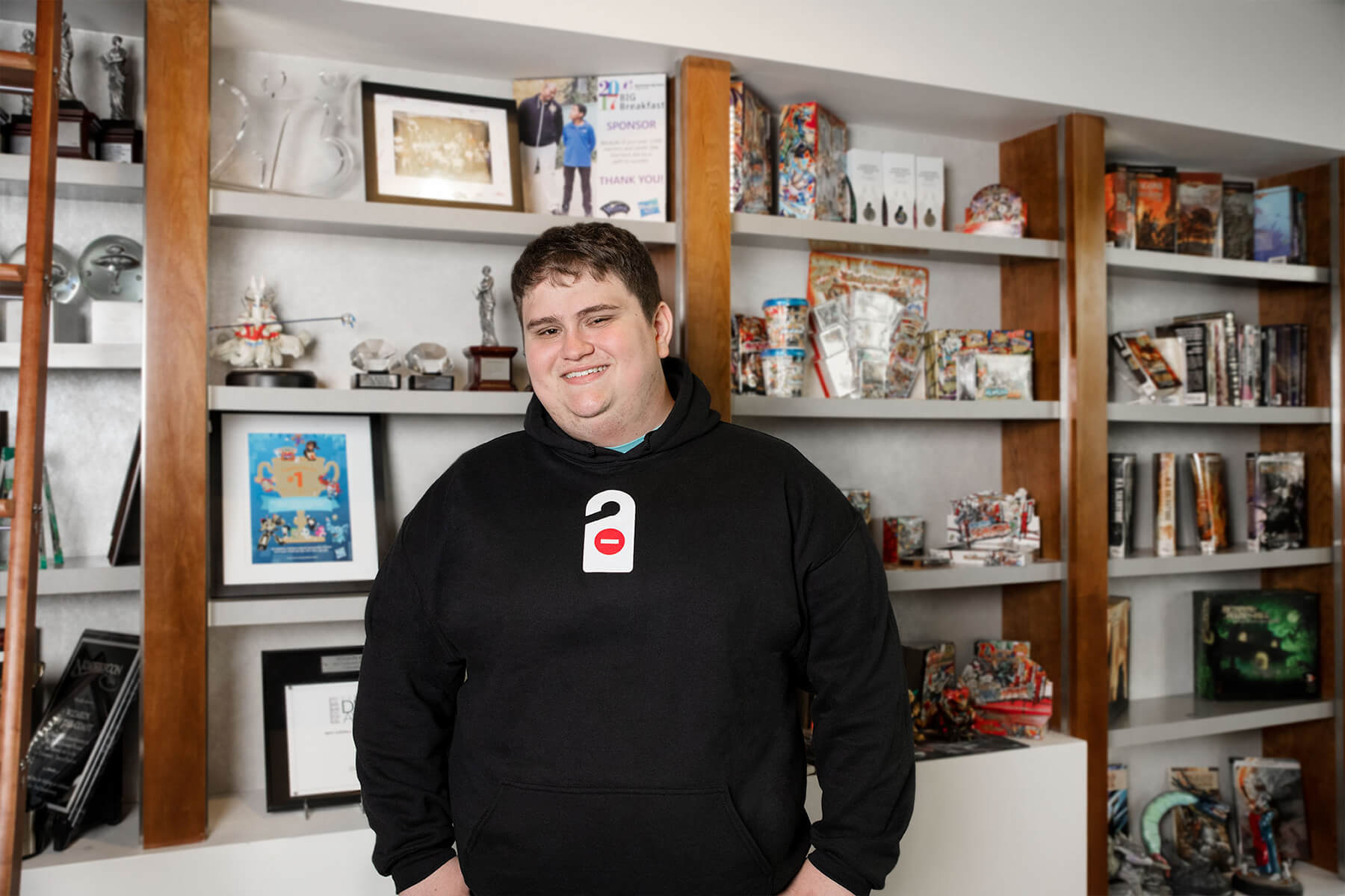 Kaan Palaz stands in front of a wall of games at Wizards of the Coast.