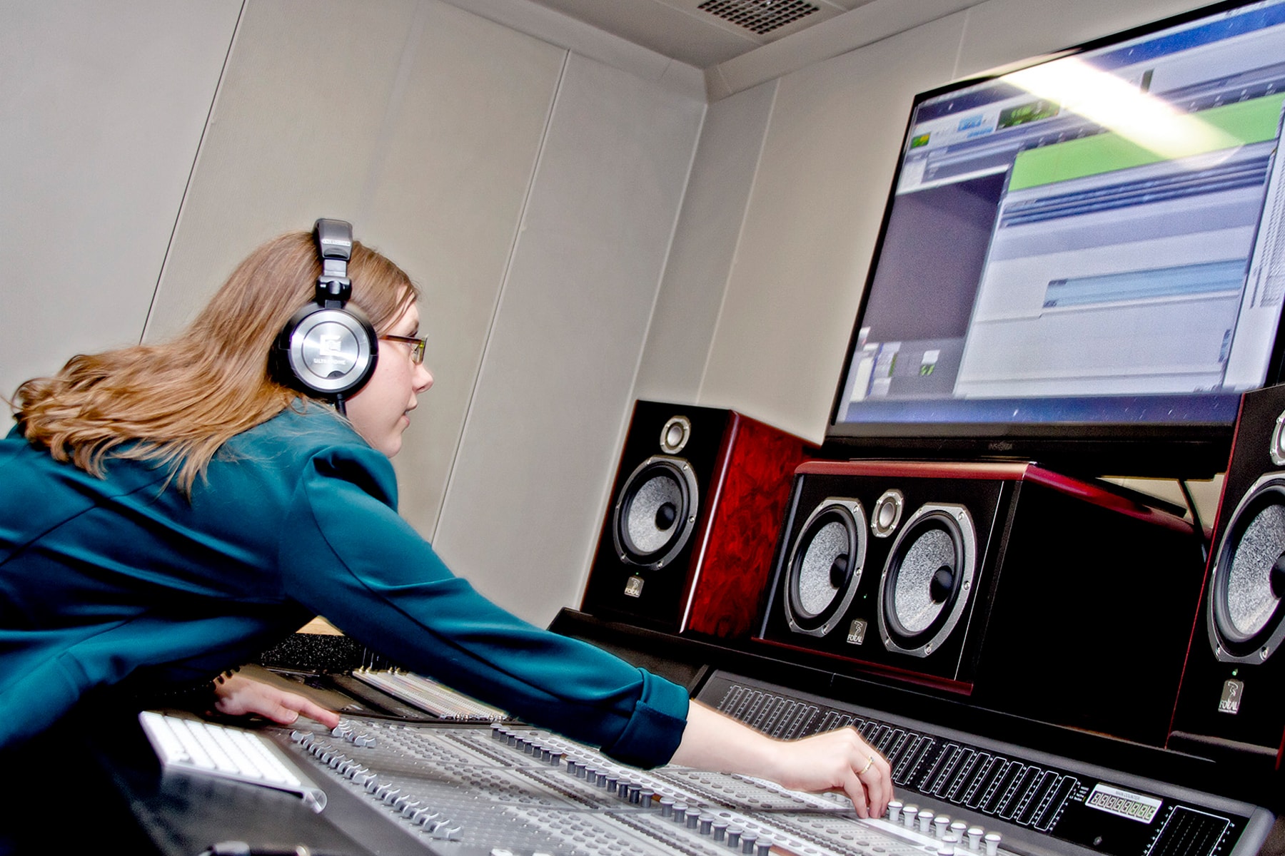 Kori Loomis working at a sound board in front of a large monitor