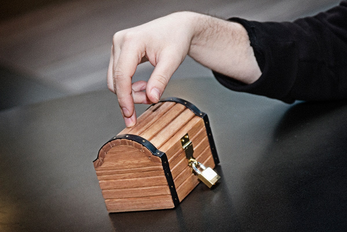 Nate Martin resting his finger on a small wooden treasure chest with a gold padlock