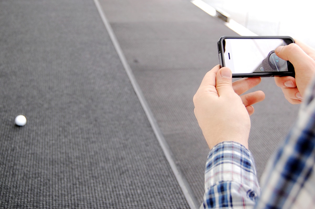 Patrick Martin using his iPhone to control the small white Sphero robotic ball