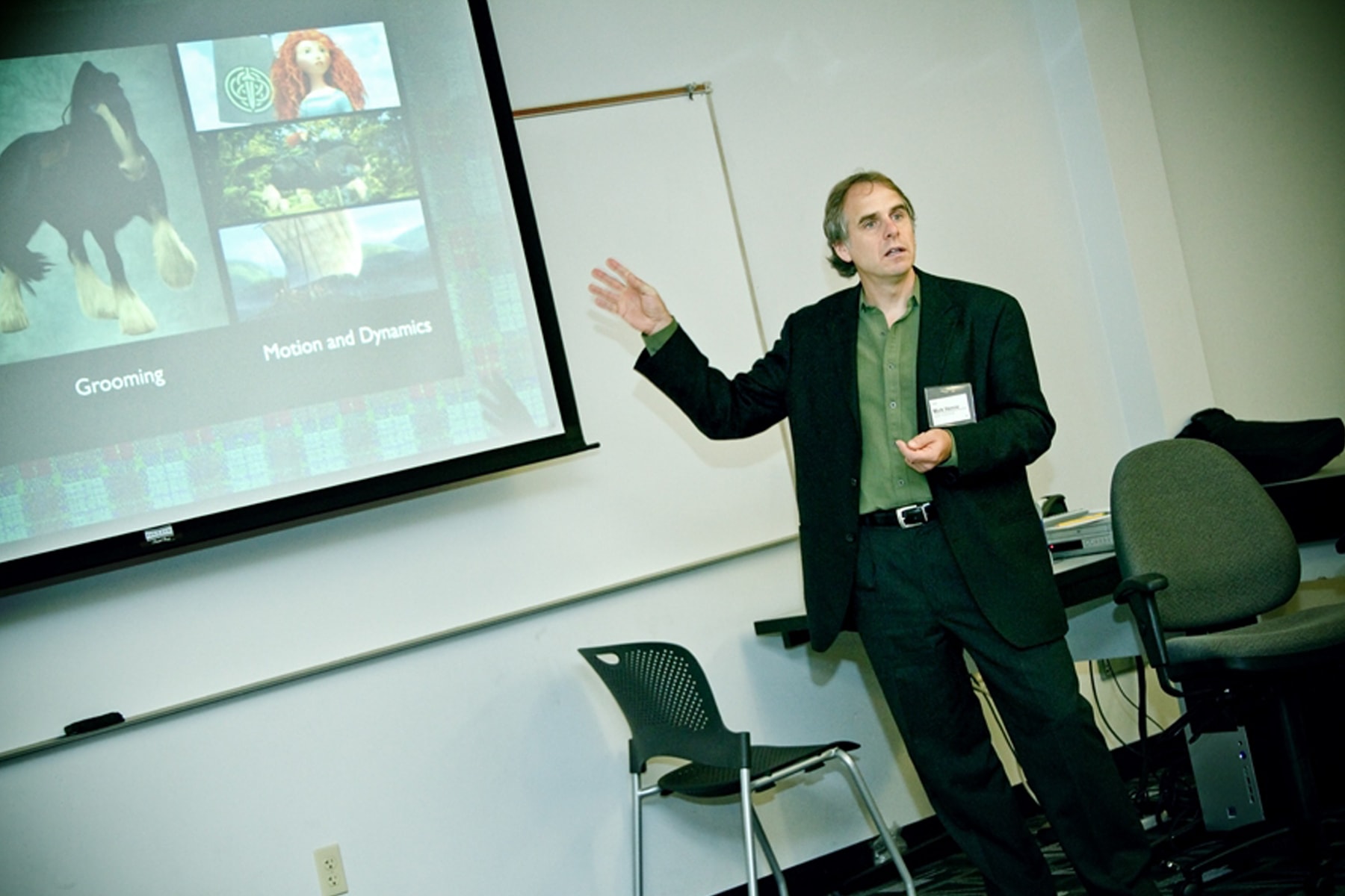 Mark Henne gestures toward a screen showing animated characters Princess Merida and her horse