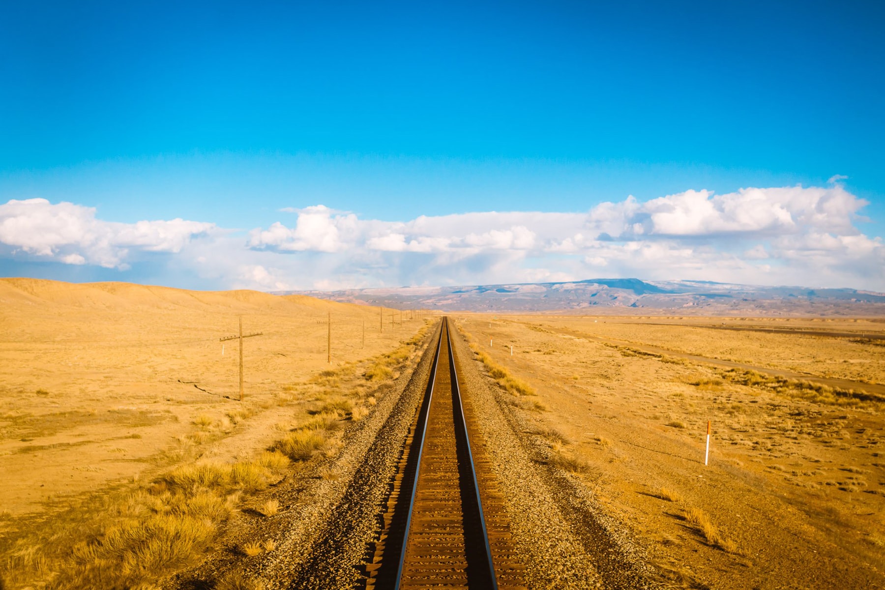 View from the back of the train of blue skies and mountains