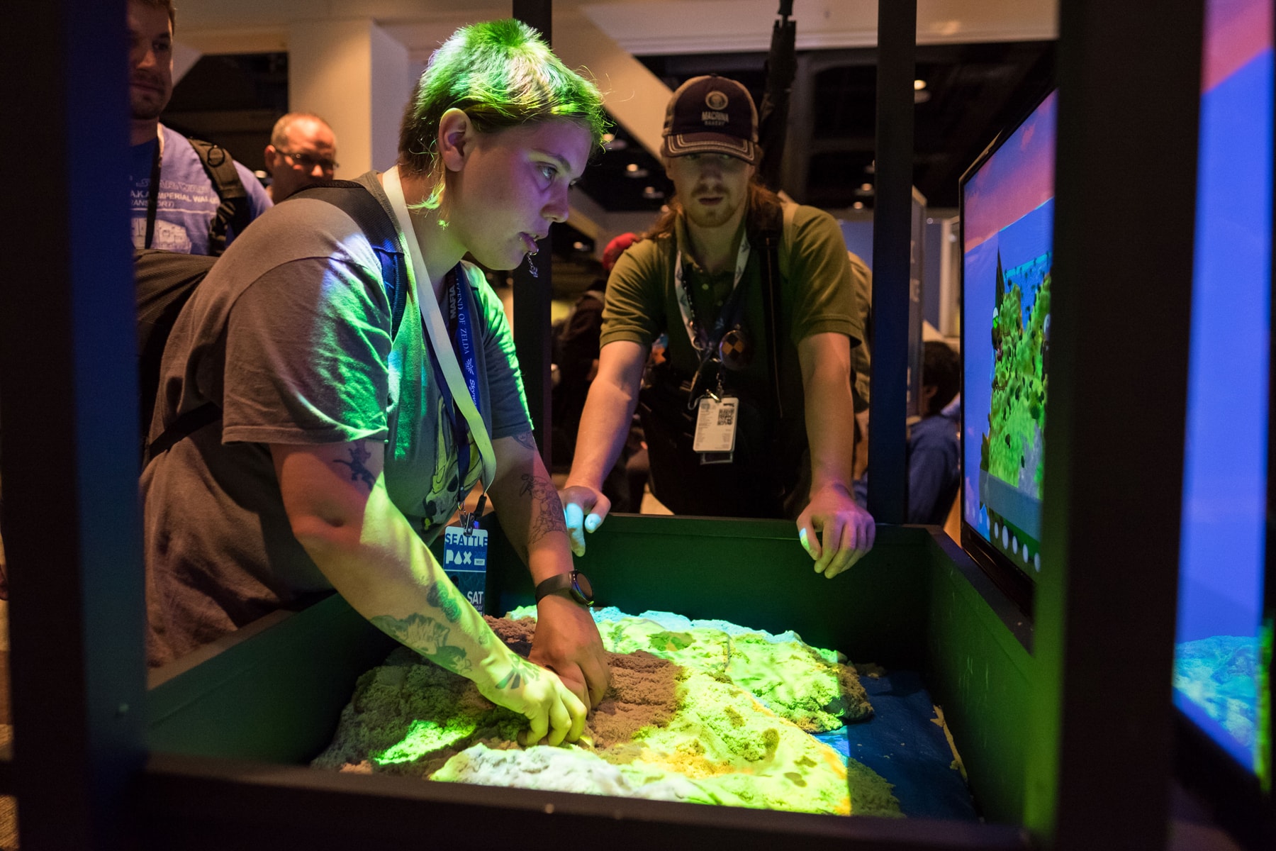 A PAX West attendee sculpting terrain by moving kinetic sand