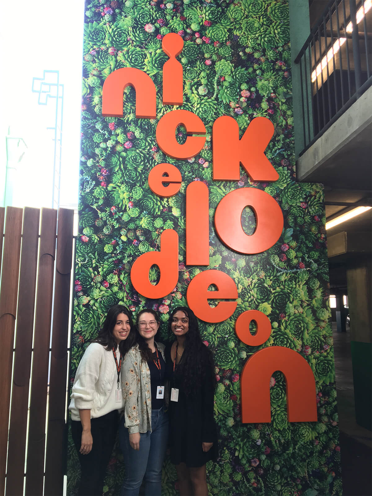 Parayil poses with two other artists in front of a Nickelodeon sign superimposed over pictures of succulents.