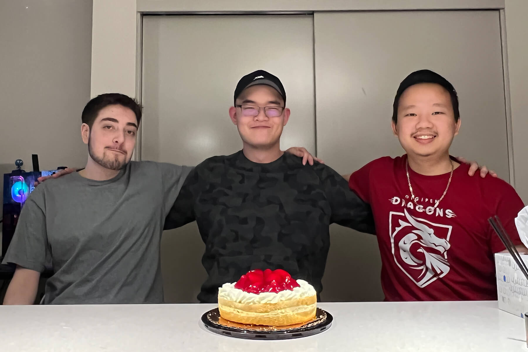 DigiPen student team Meta Fork poses with their arms over each other’s shoulders in front of a birthday cake.