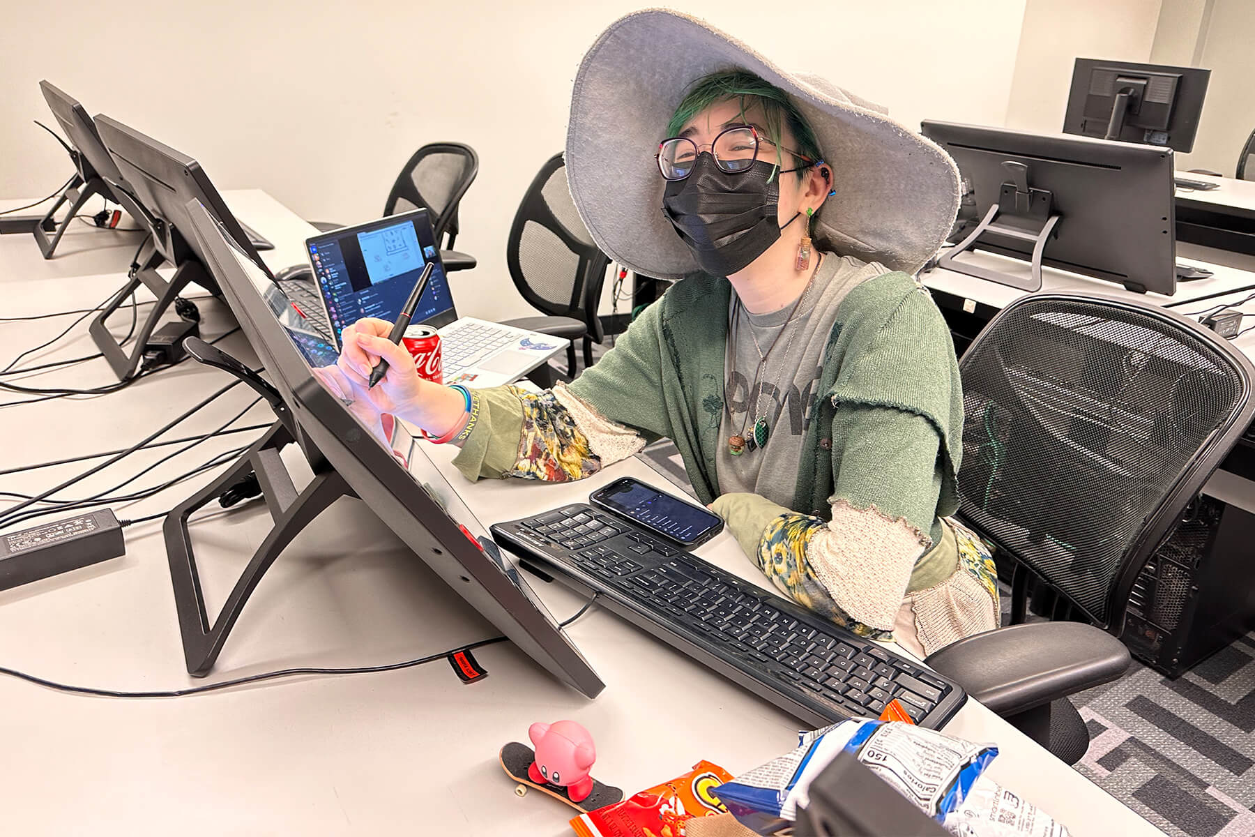 A student wearing a wizard hat draws on a tablet during the Global Game Jam.