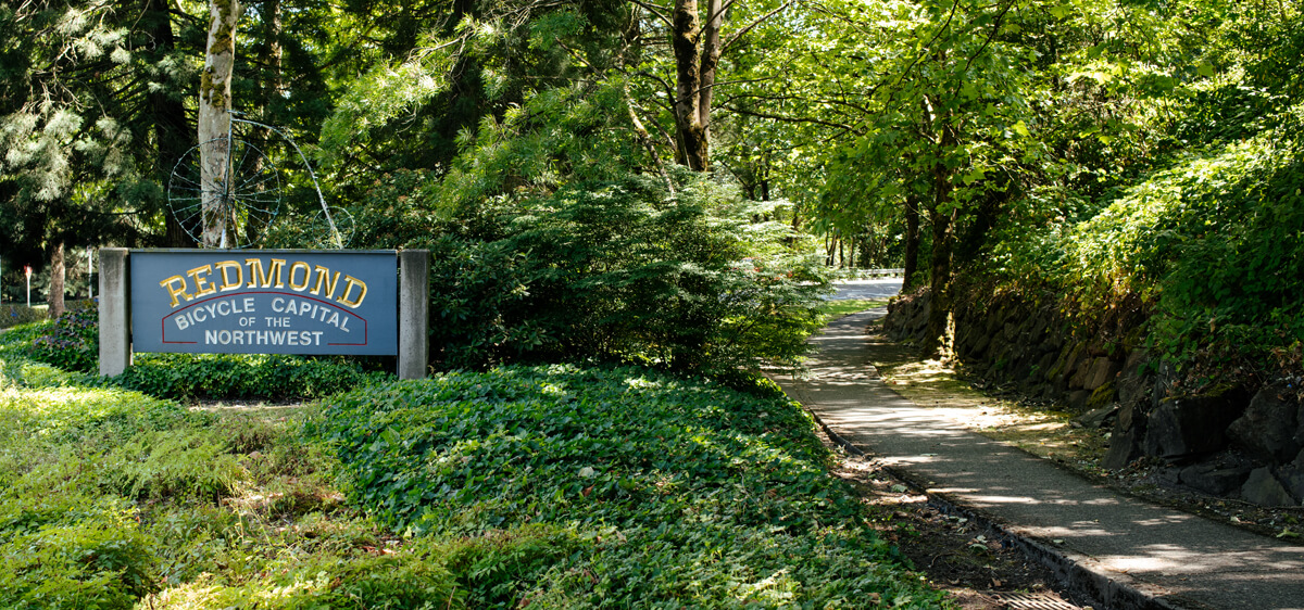 Picture of a sign reading "Redmond Bicycle Capital of the Northwest" next to a wooded trail