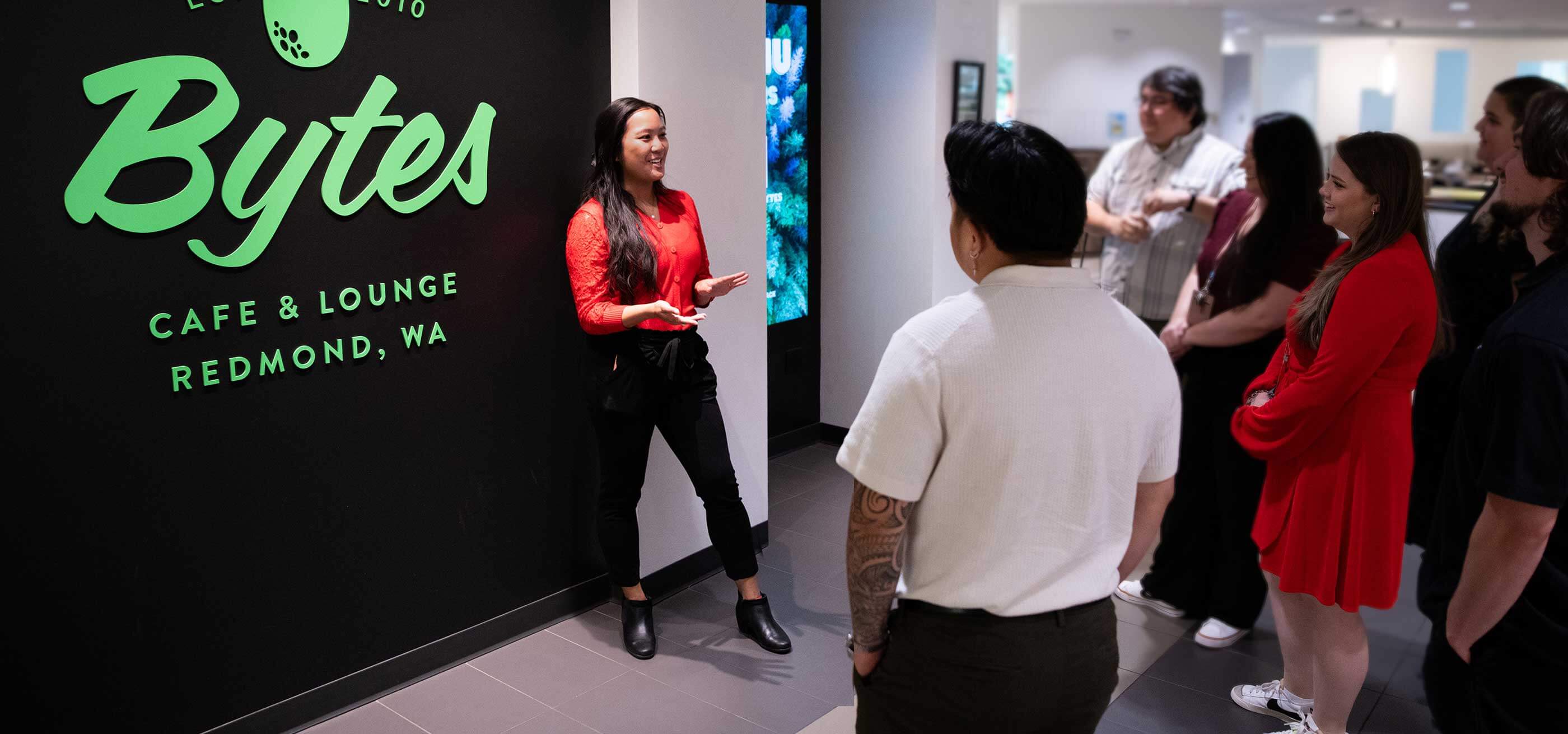 A DigiPen Outreach coordinator gestures towards a tour group in DigiPen's Bytes Cafe & Lounge.