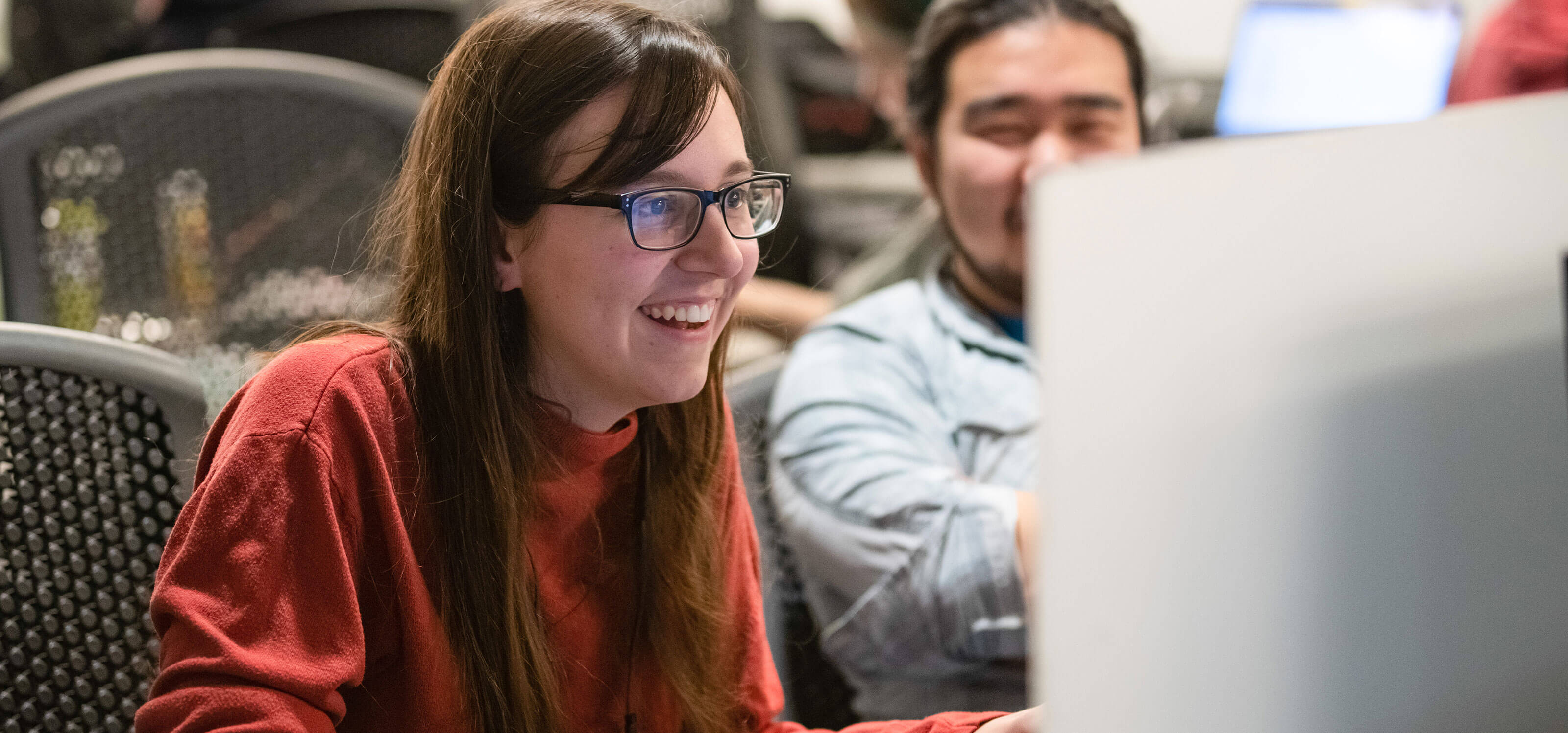 A girl looks at a computer, smiling