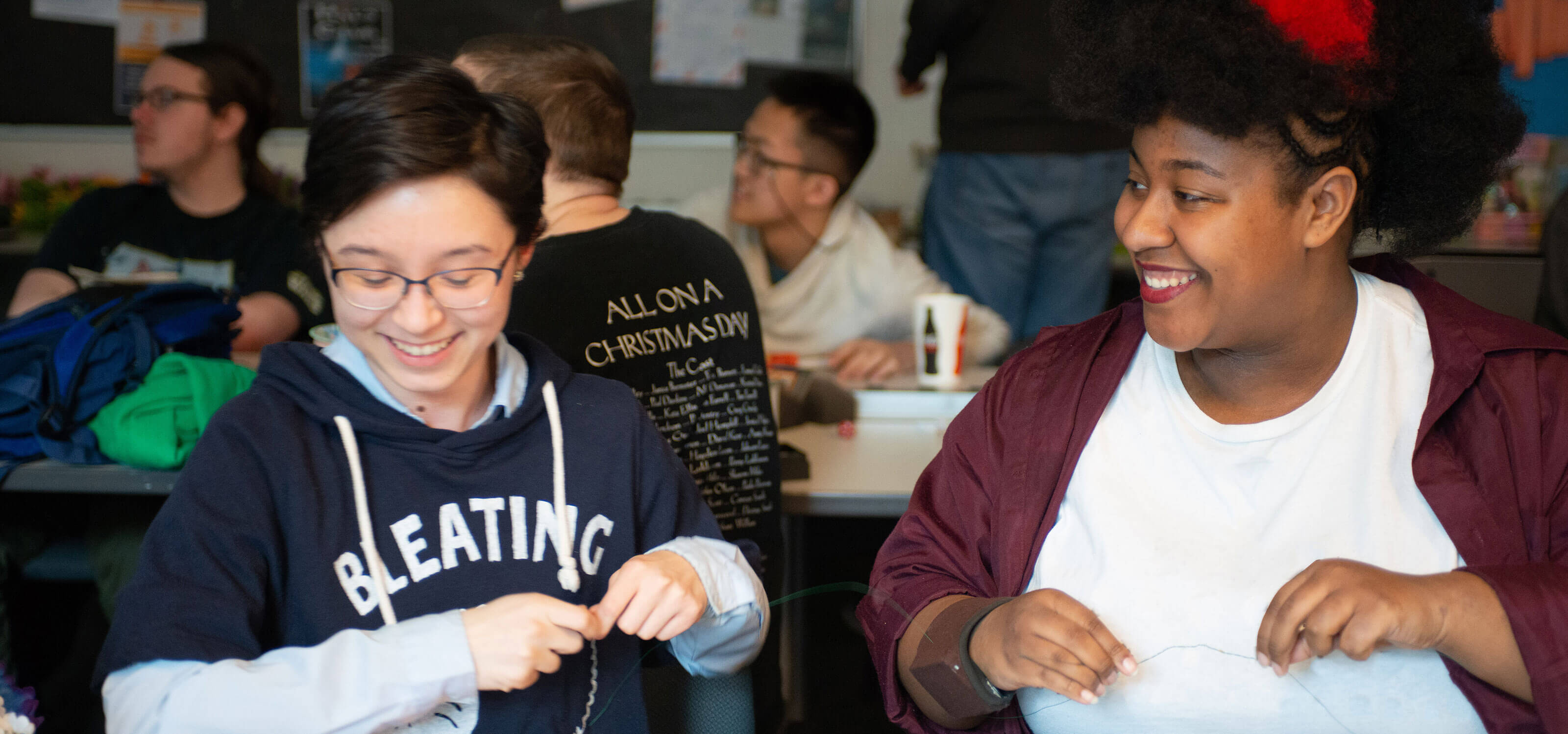 Two DigiPen students smile as they work on crafts together