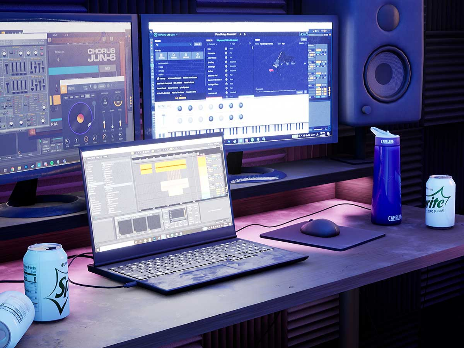A laptop and computer setup on a desk in a low-lit room.