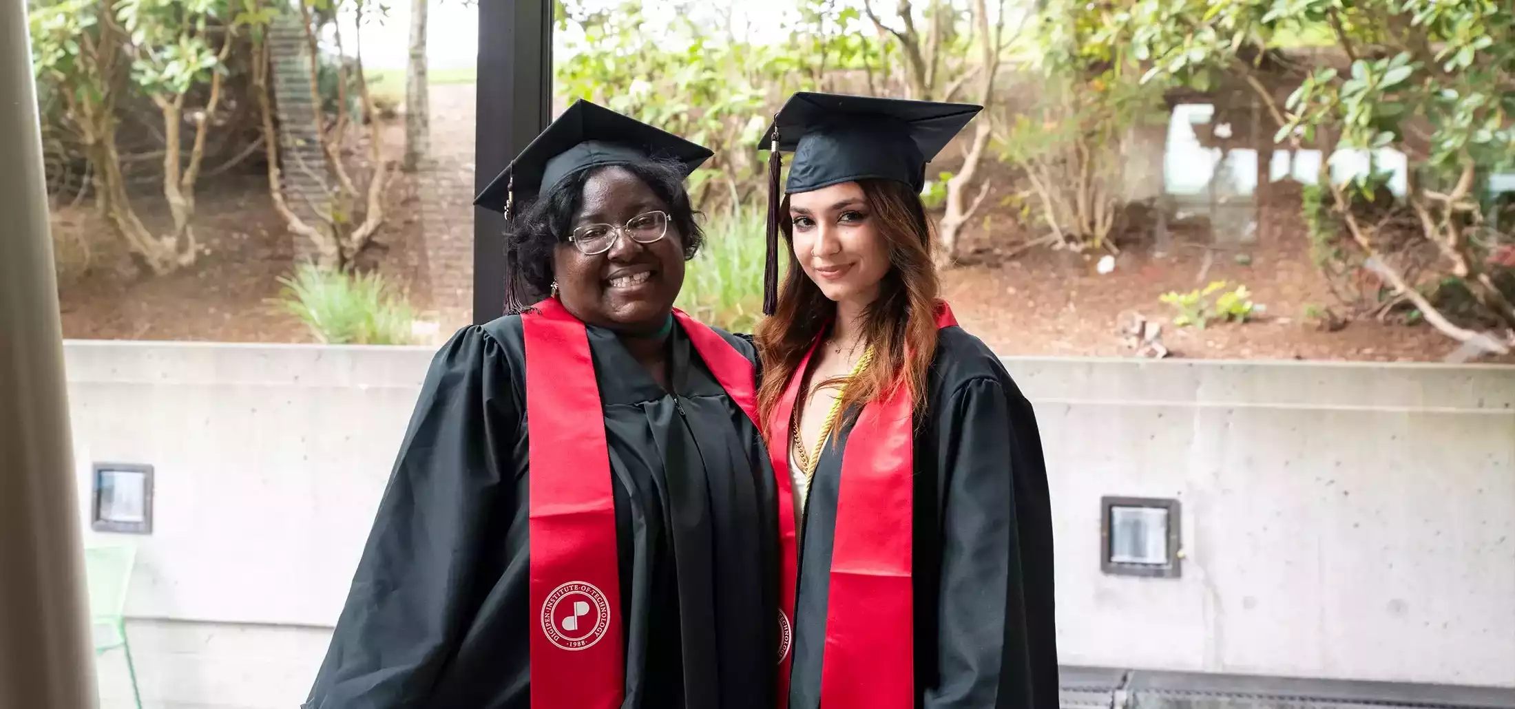 Two DigiPen animation students pose together in graduation caps and robes.