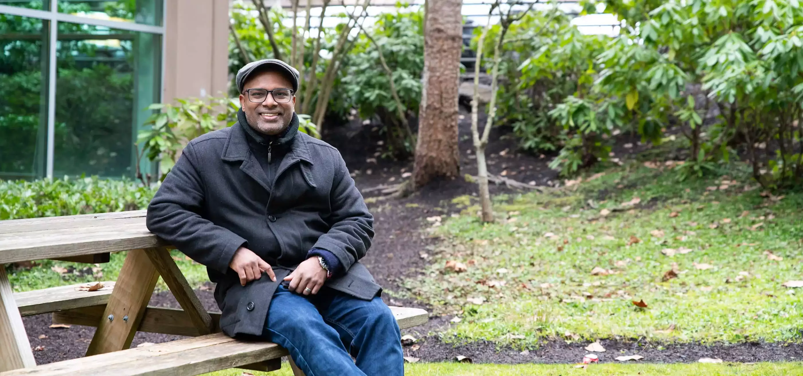 Anand Thirumalai sits at an outdoor picnic table.