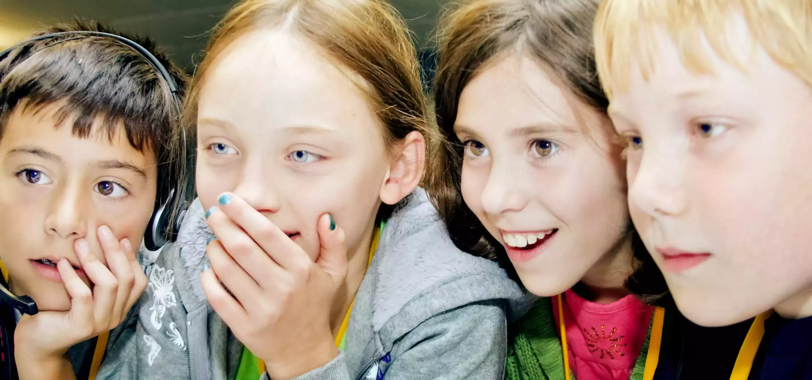 Four young ProjectFun students smiling at a computer monitor