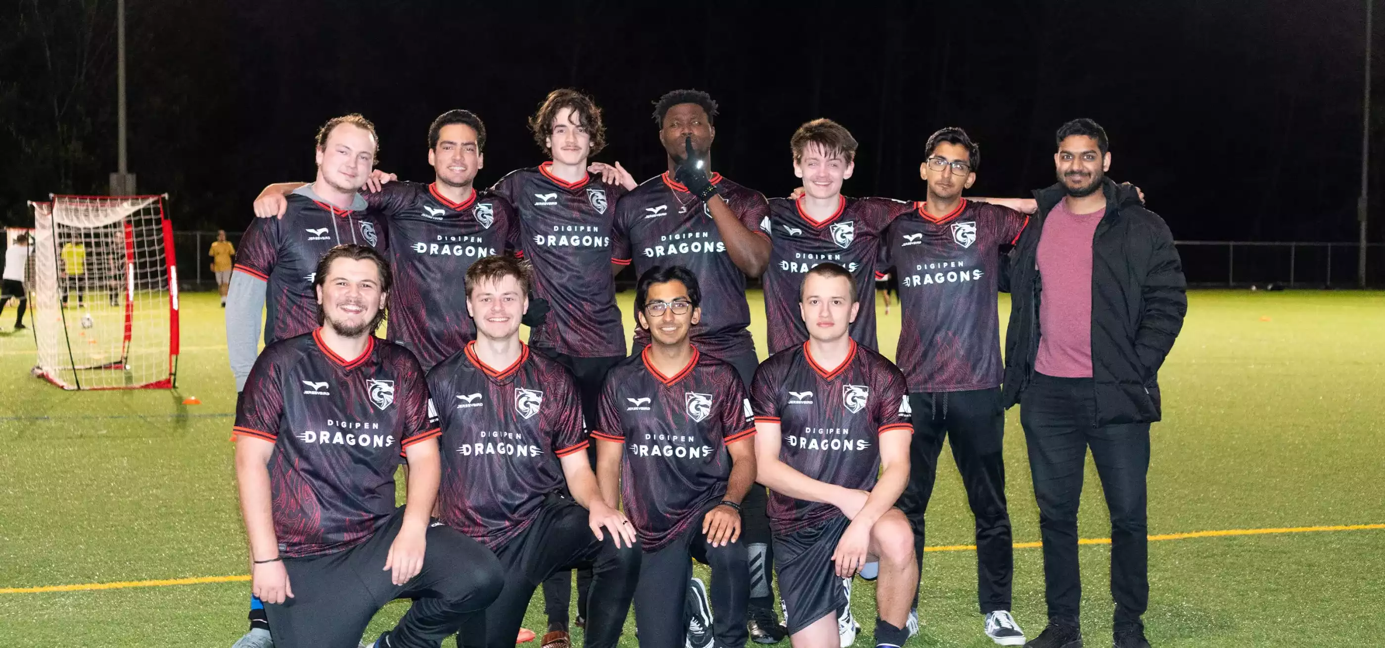 Eleven members of the DigiPen Dragons soccer team pose for a photo on the soccer field.