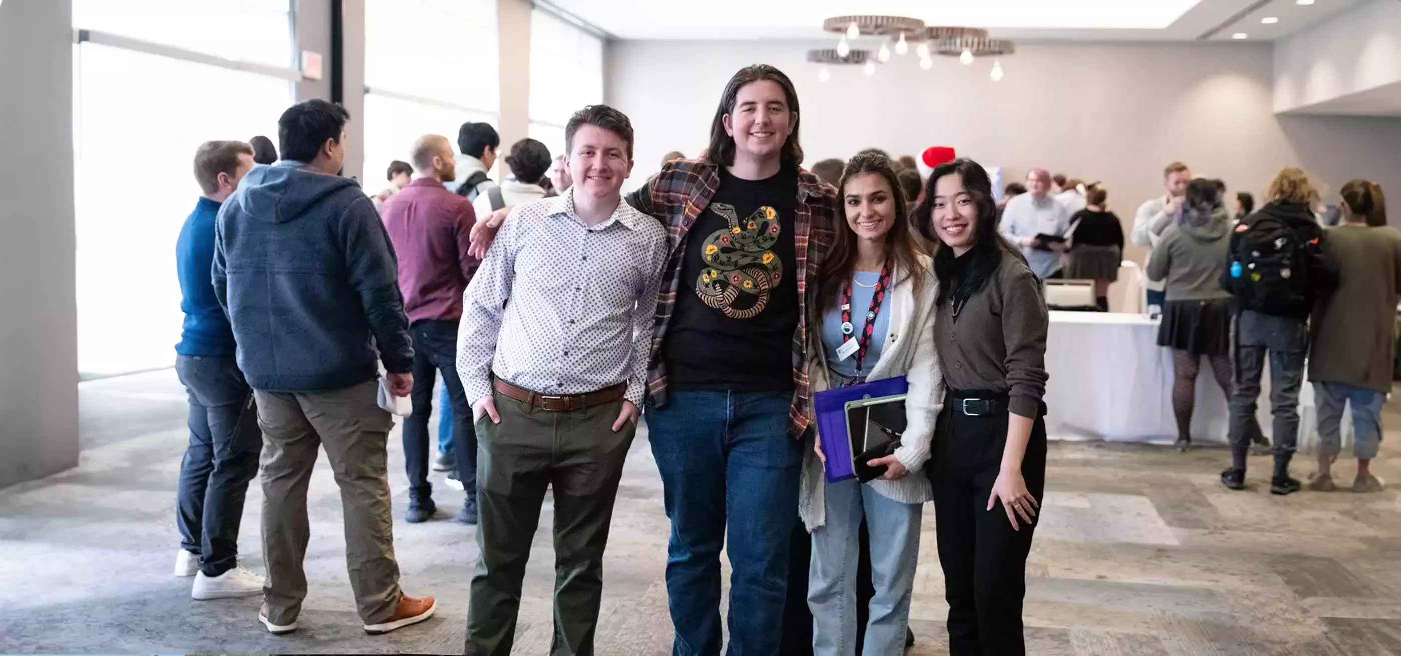 Four students pose for a photo in a conference room.