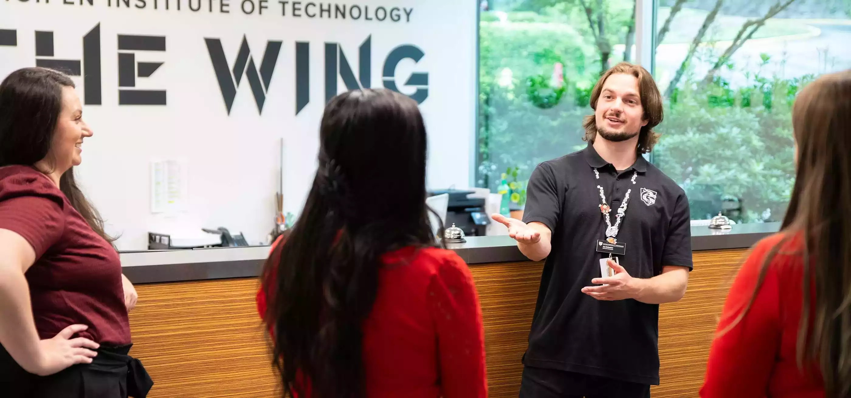 A DigiPen Outreach coordinator gestures towards a tour group in DigiPen's The Wing building.